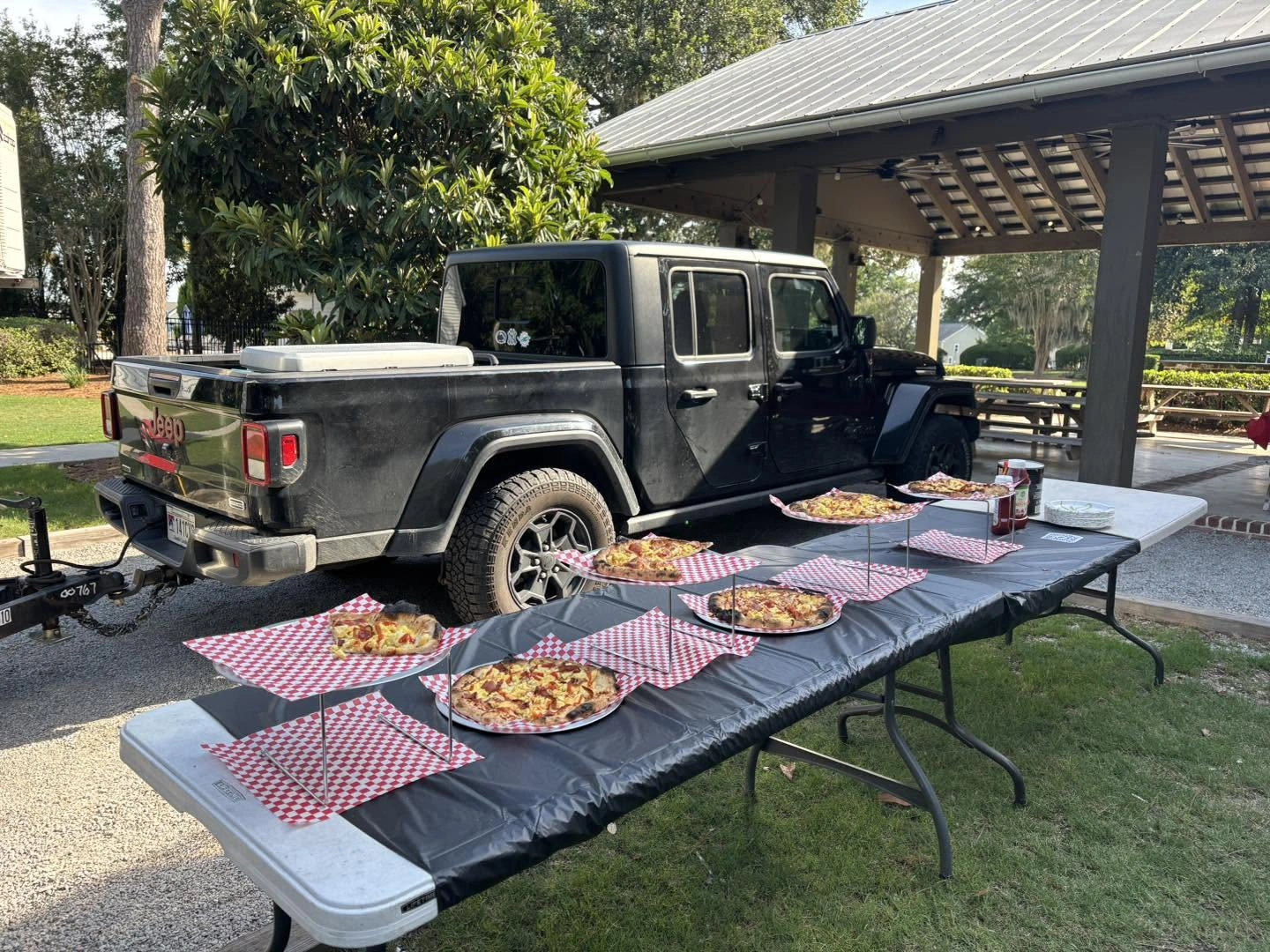The Holy Smokes Pizza trailer beside a table of fresh wood-fired pizzas